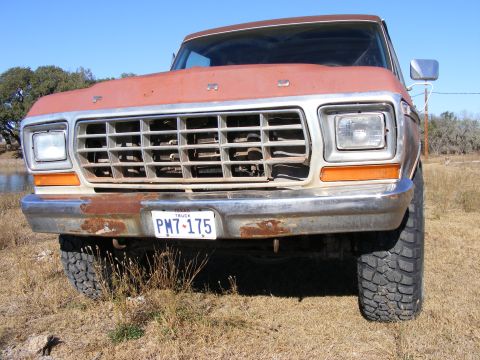 1979 Ford Bronco - Front view of a rusty orange Ford pickup truck with a chrome bumper and a Texas license plate reading "PM7-175". The truck is parked outdoo…