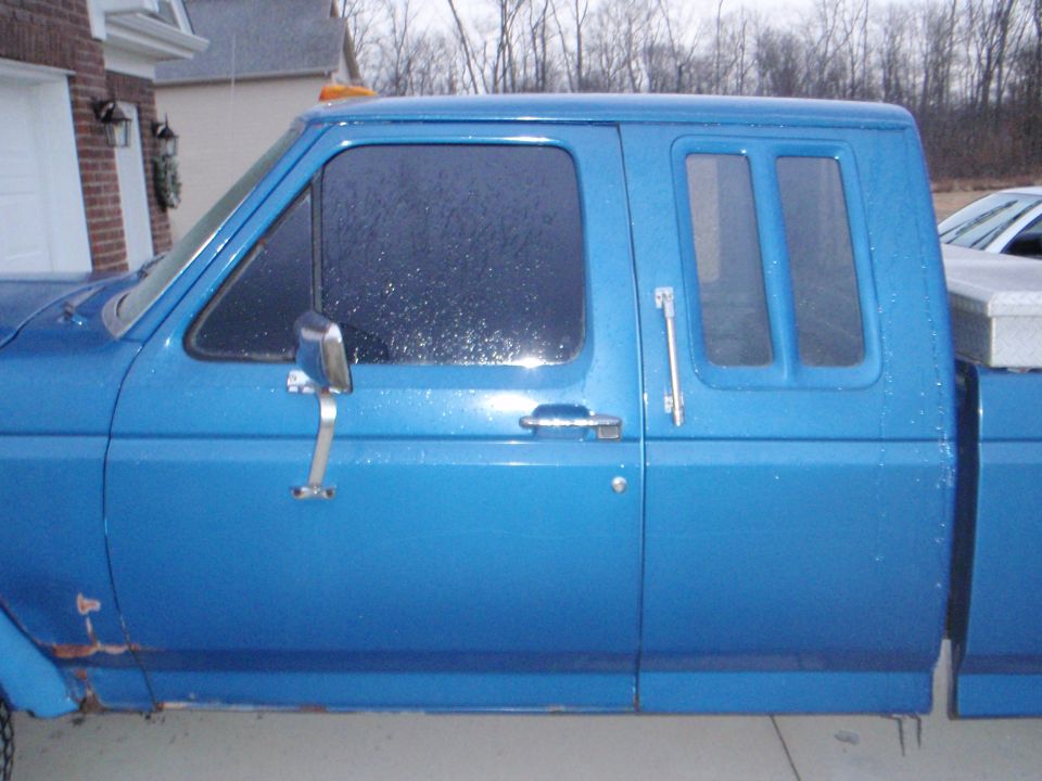 Blue Ford F-250 pickup truck, driver's side view, showing door and rear cab window.