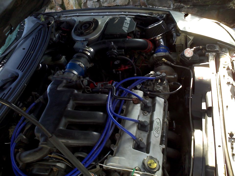 Modified engine bay with turbo, AEM air intake, and blue spark plug wires.