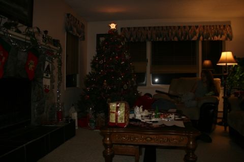 1990 Chevrolet Suburban - A dimly lit living room is decorated for Christmas with a tree, stockings hung by the fireplace, and presents on a coffee table. A woman si…