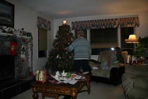 1990 Chevrolet Suburban - A person is decorating a Christmas tree in a living room. A young woman is sitting in a chair nearby.