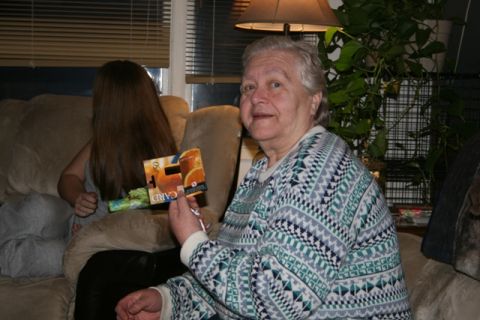 1990 Chevrolet Suburban - An elderly woman is holding a gift card with oranges on it, while a younger person with long brown hair sits on a couch behind her. The wom…