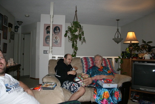 People opening gifts on a couch in a living room.