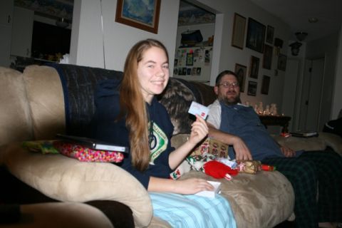 1990 Chevrolet Suburban - A young woman smiles as she holds up a gift card while sitting on a couch with a man. Presents are visible on the couch around them.