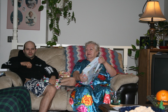 Woman holding a gift box on a couch with a man next to her.