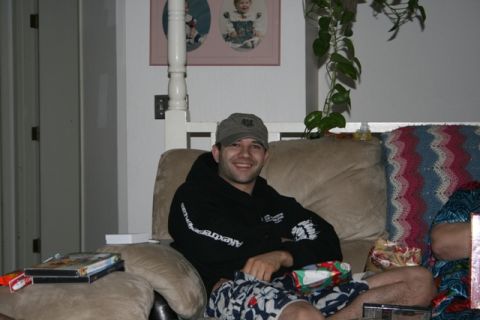 1990 Chevrolet Suburban - A man wearing a baseball cap and a black hoodie sits on a couch with Christmas presents around him.