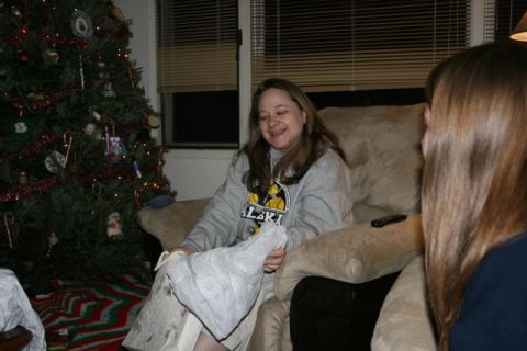 1990 Chevrolet Suburban - A woman is sitting on a couch next to a Christmas tree and unwrapping a gift. Another person's hair is visible in the foreground.