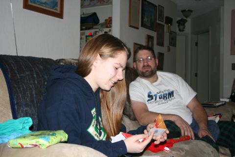 1990 Chevrolet Suburban - A young woman and a man are sitting on a couch, looking at cards or gift tags. The woman is wearing a dark blue hoodie, and the man is wear…