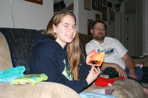 1990 Chevrolet Suburban - A young woman smiles while holding up a gift card in front of a man sitting on a couch.