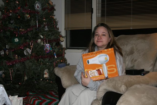 Woman holding a Vidal Sassoon hair dryer box next to a Christmas tree.