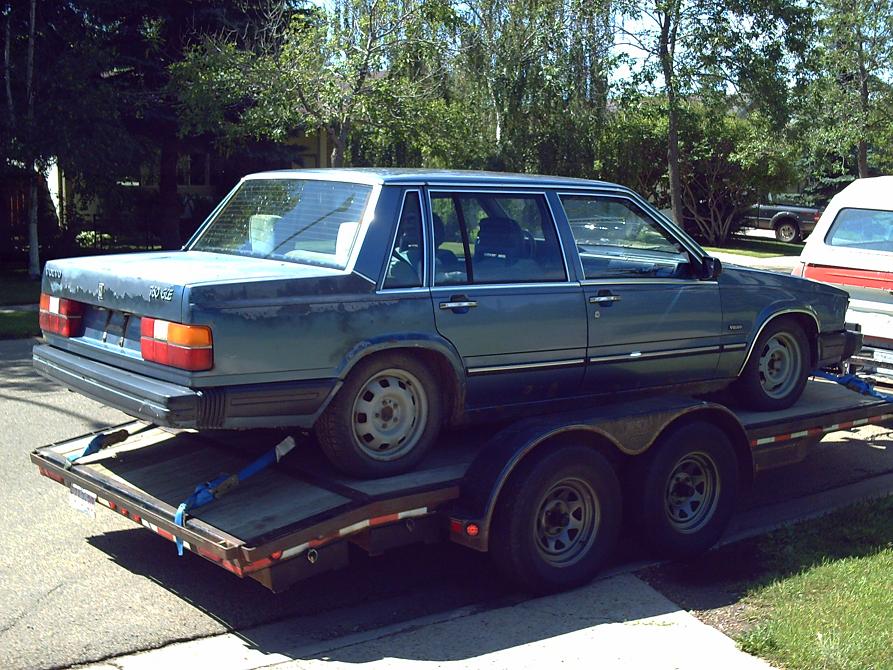 Blue Volvo 760 sedan on a trailer, rear 3/4 view.