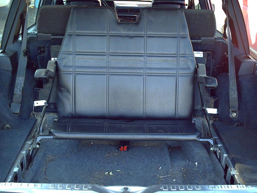Black rear seat in a wagon cargo area with grey carpet and metal seat frames