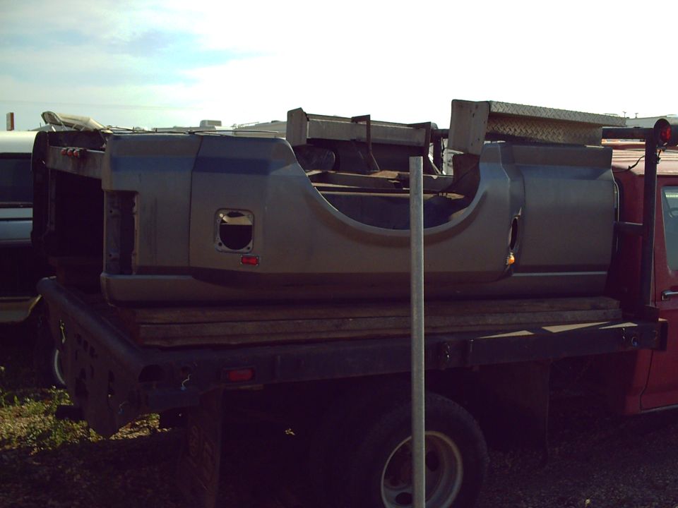 Gray truck bed with blue accents loaded on a flatbed trailer.