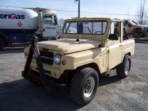 1991 Ford Bronco - A tan, 1990s era utility vehicle with a soft top is parked outdoors next to a large white tanker truck. The vehicle has a front brush guard…