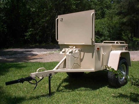 1991 Ford Bronco - A tan utility trailer with two jerry cans mounted on the front is parked on a grassy area next to a wooded background.