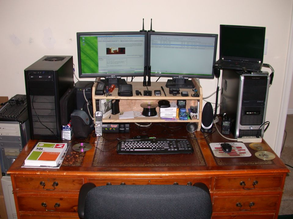 Desk with multiple computers, monitors, keyboard, mouse, and office supplies.
