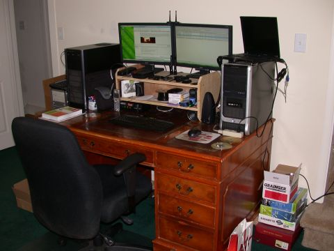 2000 Ford Crown Victoria - A wooden desk with two computer monitors, a desktop tower, a laptop, a black office chair, and various computer accessories. Several boxes…