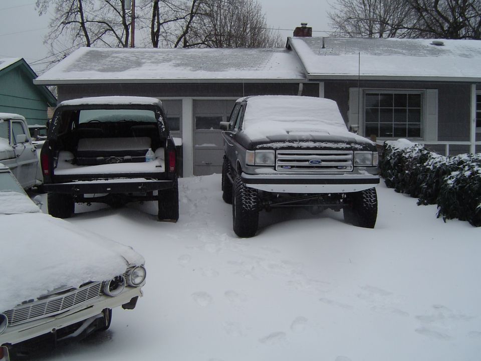 1989 Ford Bronco and another truck covered in snow in a driveway.