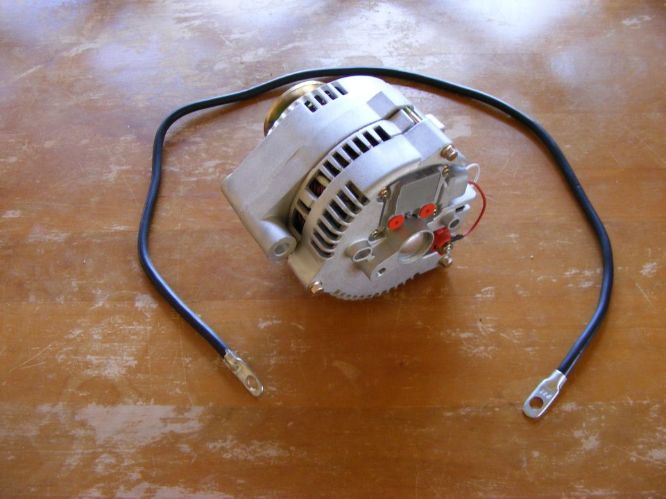 Bare automotive alternator with battery cable on wood surface
