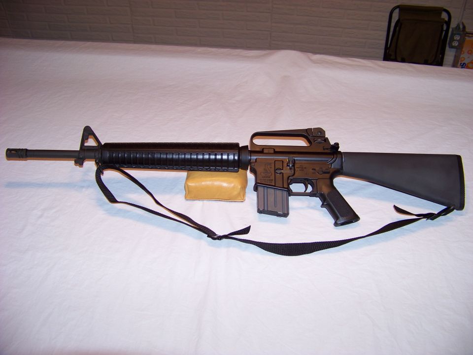 Black rifle with sling on white surface