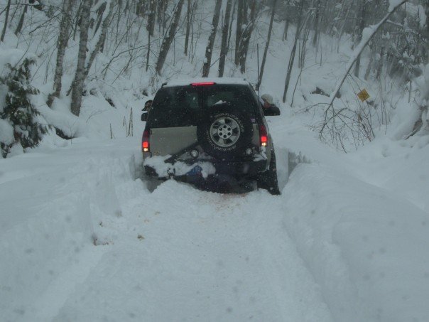 Chevrolet Tahoe stuck in deep snow on a wooded road, rear view.
