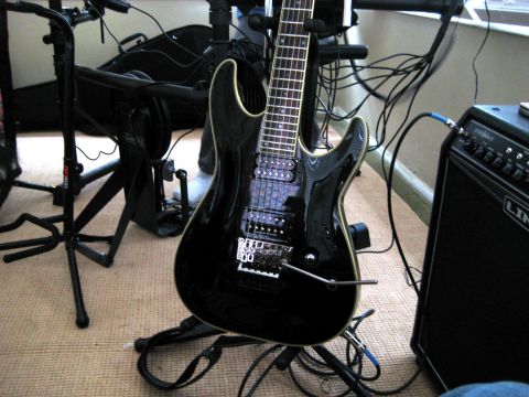 1996 Ford Bronco - A black electric guitar is on a stand, connected to an amplifier. Various cables and music equipment are visible in the background.
