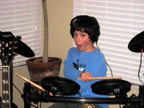 1996 Ford Bronco - Young boy with headphones on plays an electronic drum set with drumsticks.