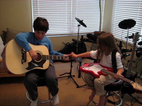1996 Ford Bronco - Two children are learning to play guitars in a room with blinds covering the window.