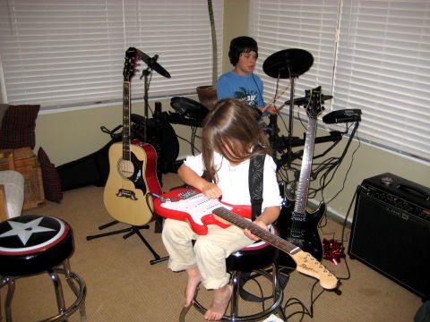 1996 Ford Bronco - Two children are engrossed in playing musical instruments, one with a red electric guitar and the other at a drum set.
