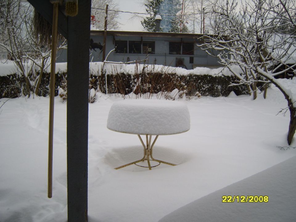 backyard covered in snow with a table in the middle