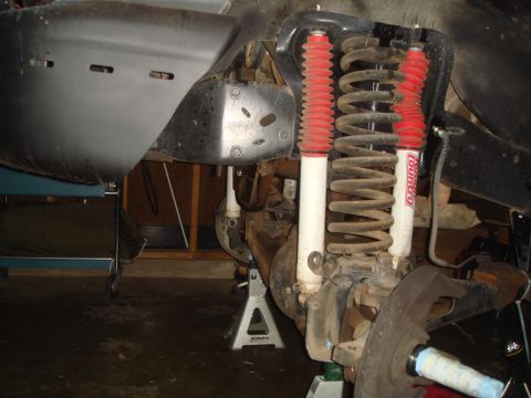 1992 Ford Bronco - Close-up view of vehicle suspension components, including shocks and springs, supported by jack stands.