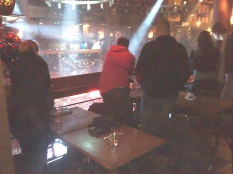 1991 Ford Crown Victoria - People gather indoors, illuminated by dramatic spotlights, with tables and railings visible.