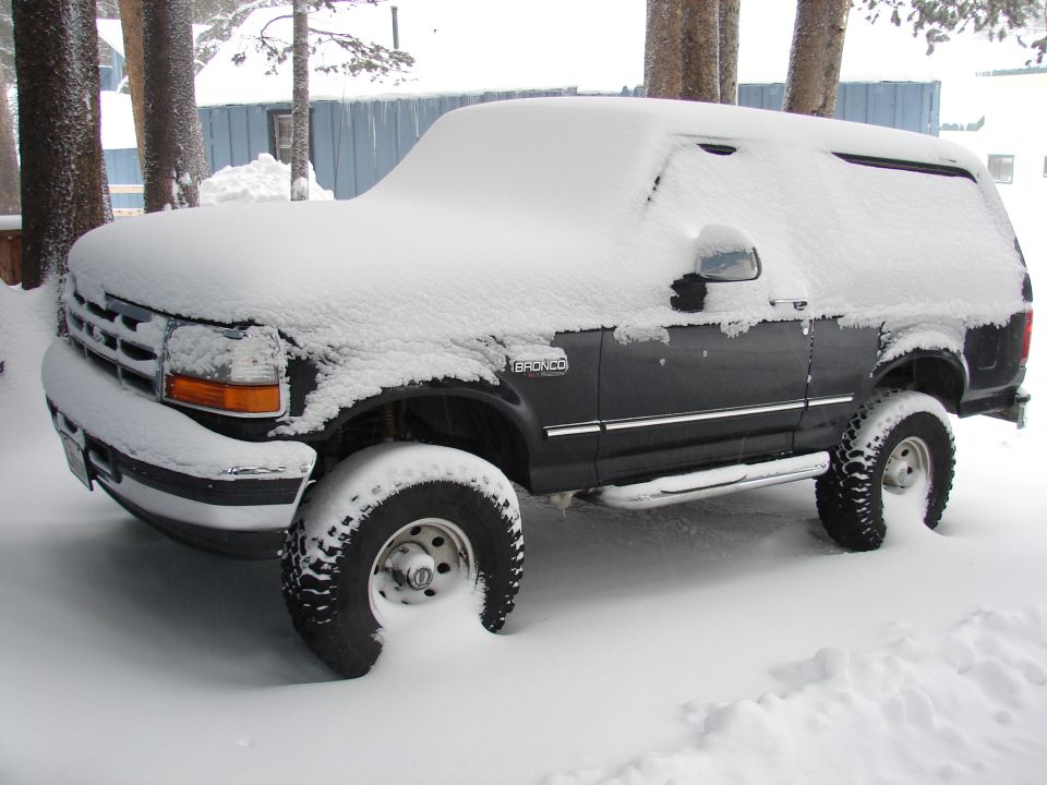 Dark 1996 Ford Bronco covered in snow, 3/4 front view
