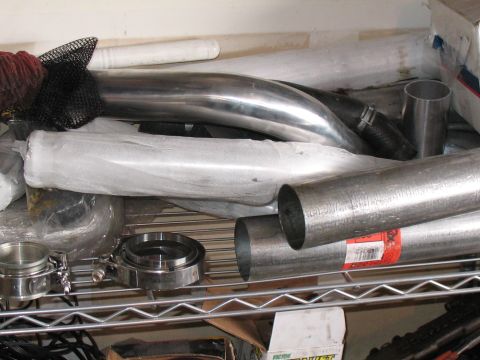 2001 Pontiac Trans Am - Various metal pipes and exhaust components are stored together on a wire shelf.