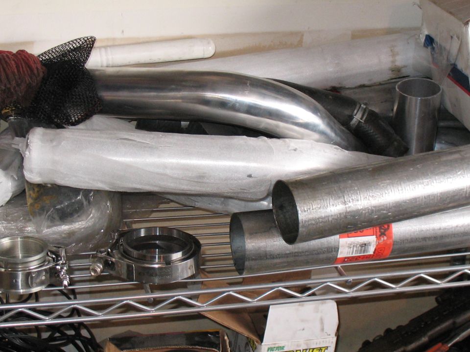 Pile of exhaust pipes and V-band clamps on a shelf