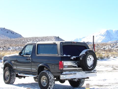 1996 Ford Bronco - A 1996 Ford Bronco is seen in a snowy landscape with mountains under a clear blue sky.