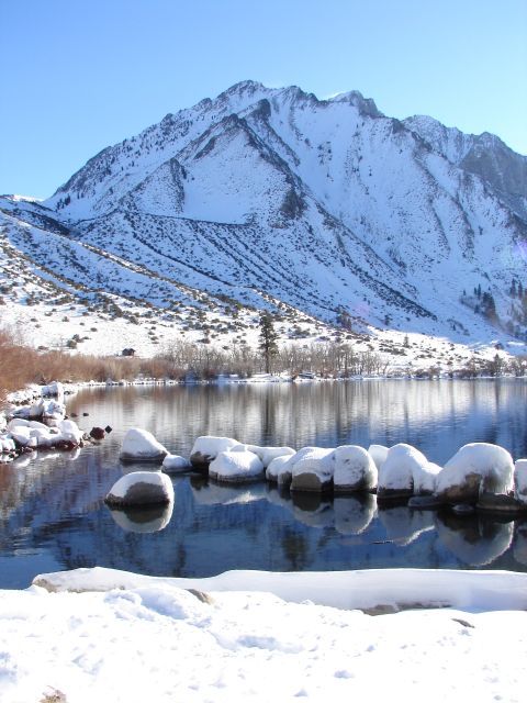 1996 Ford Bronco - A winter scene unfolds with a snow-dusted mountain overlooking a tranquil lake dotted with icy rocks.