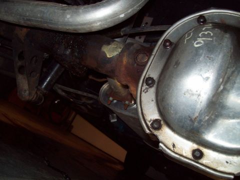 1999 Mercury Grand Marquis - Underside close-up of a rear axle housing with a bare bolt-on differential cover hand-marked in white grease pencil, next to the rusty axle…
