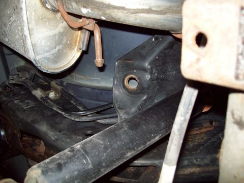 1999 Mercury Grand Marquis - Tight underbody detail of a black-painted rear suspension bracket with an empty bushing eyelet, mounted near the frame with a black bar pas…