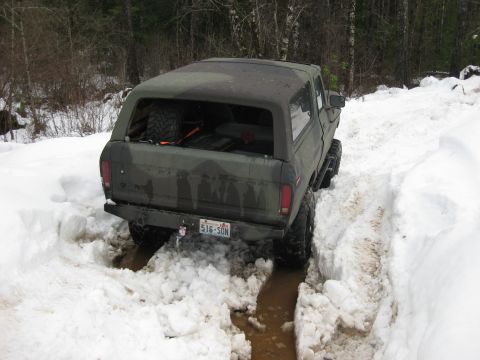 1979 Ford Bronco - Ford Bronco with camouflage paint navigating a snowy and muddy trail.