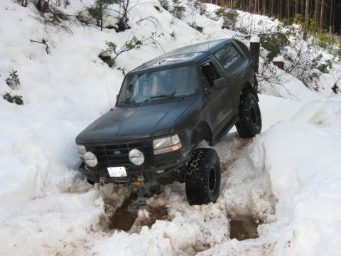 1979 Ford Bronco - This SUV navigates a snowy path, its lifted suspension and large tires clearly visible.