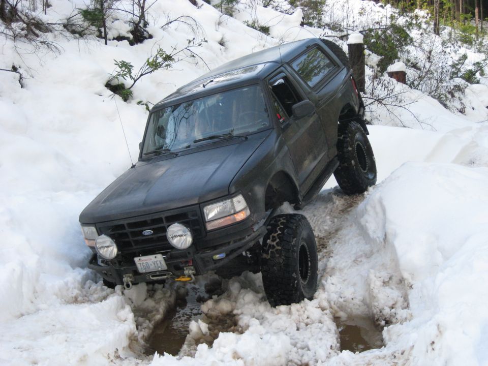 Dark SUV with large tires navigating a snowy trail