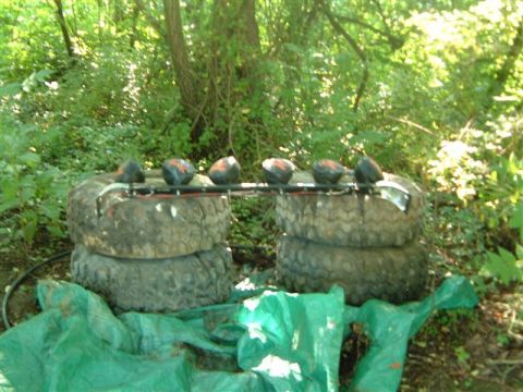 1982 Ford Bronco - Off-road lights are mounted on a bar supported by stacked tires in a natural setting.