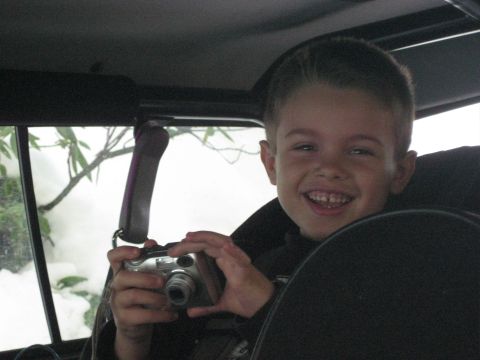 1979 Ford Bronco - A young boy smiles while holding a digital camera inside a vehicle.