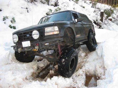1979 Ford Bronco - Modified Ford Bronco navigating a snowy trail with deep ruts.