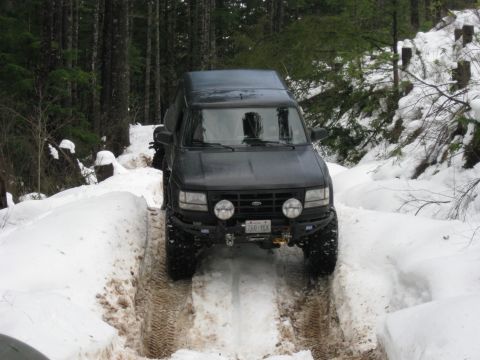 1979 Ford Bronco - This dark SUV navigates a snowy path in a wooded area, its tires leaving tracks in the snow.