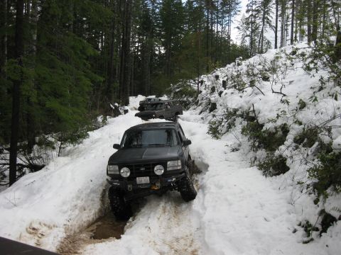 1979 Ford Bronco - Several SUVs traverse a challenging snow-covered mountain road during a winter excursion.