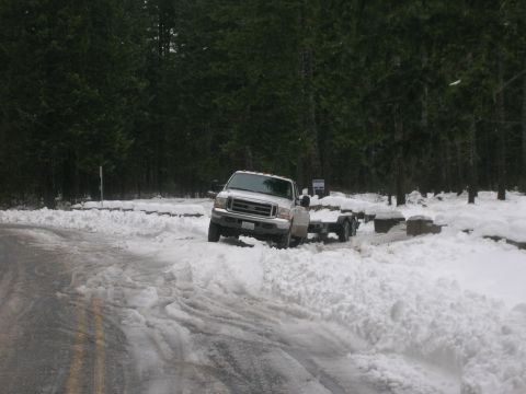 1996 Ford Bronco - White Ford F-250 Super Duty truck towing a trailer in snow, likely a campground or rest stop.