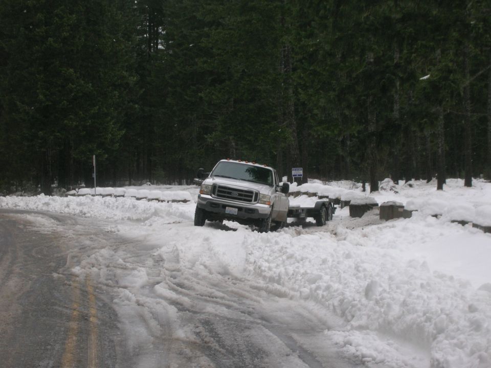 White Ford F-250 Super Duty truck towing a trailer in snow. Grille indicates 2005 model year