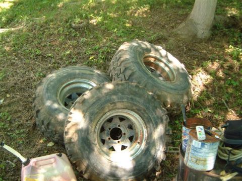 1982 Ford Bronco - Several large off-road tires are stacked on the ground, suggesting a vehicle repair or modification project.